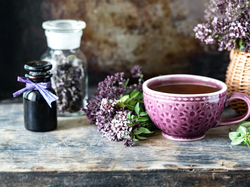 Herbal tea with dried botanicals and apothecary jars on a rustic table