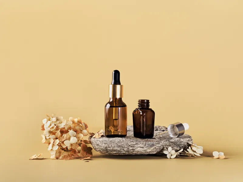Amber dropper bottles on a stone with dried florals